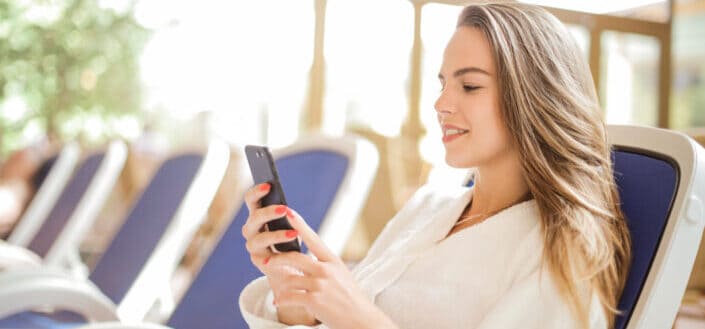 Woman in white bathrobe using a smartphone