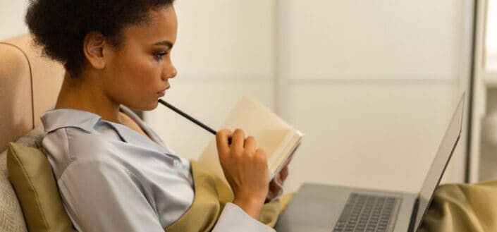Woman lying on a bed using laptop