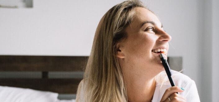 Woman smiling while holding a pen