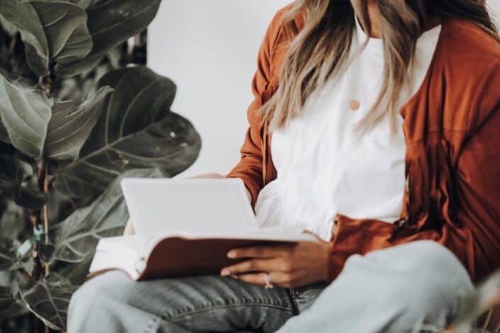 Woman wearing brown leather jacket reading a book