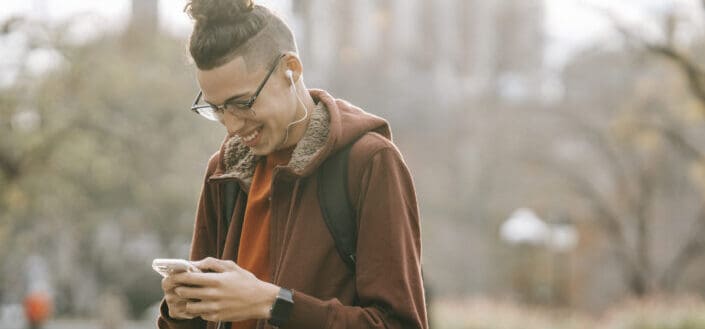 Guy with backpack smiling while listening to music