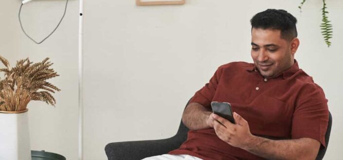 Man Sitting on Chair Holding a Cellphone