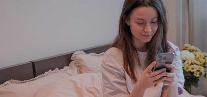 Woman Sitting in Bed Holding a Cellphone
