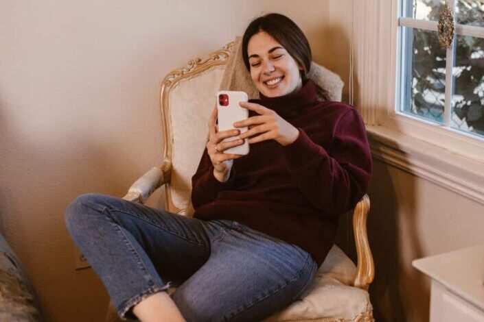 Woman On Chair Smiling At Phone