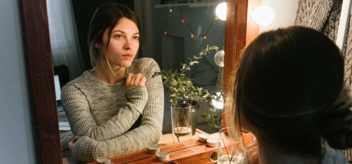 Woman in Gray Sweater Looking in a Mirror