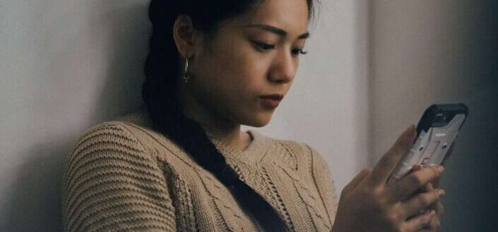 woman leaning on wall and using smartphone