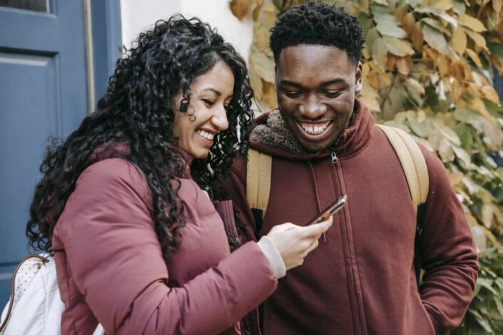 Cheerful Couple Smiling at Their Smartphone