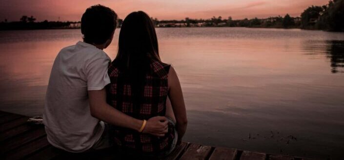 man and woman sitting on dock