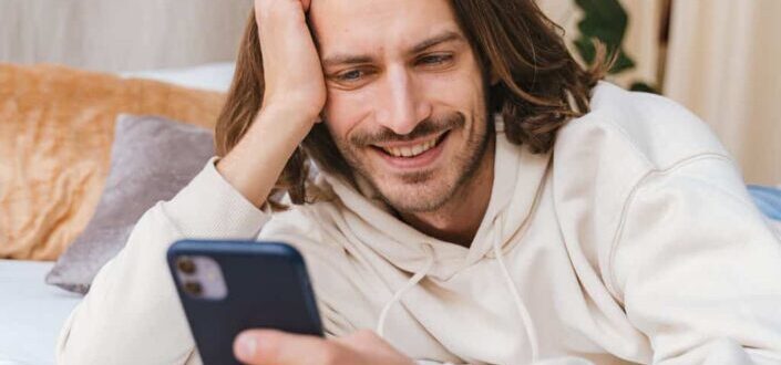 Man Lying on a Bed While Texting