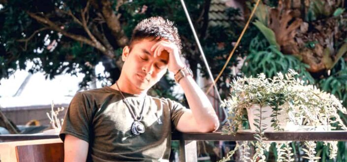 Man Sitting Outside Holding His Head