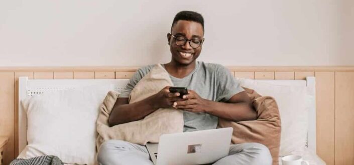 Man sitting on bed while using cellphone