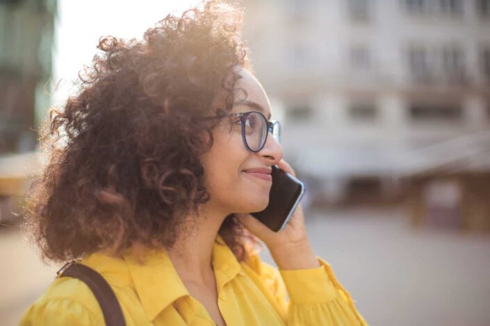 Woman Wearing Eyeglasses Smiling While Listening to Her Phone
