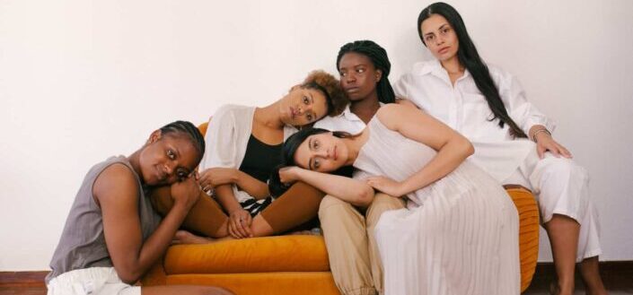 women sitting on orange sofa