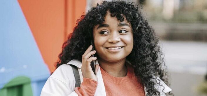 Smiling Woman Talking on Smartphone While on the Street