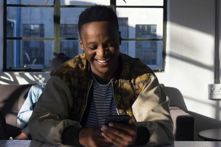 man smilling while holding his smartphone
