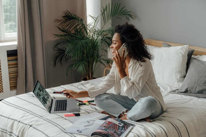 Woman Using a Laptop While Having a Phone Call