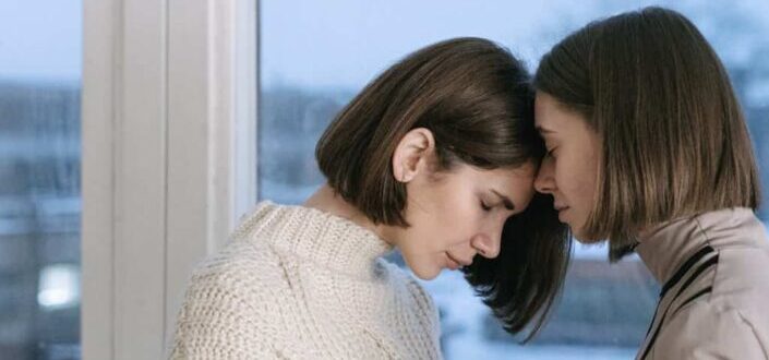 Women comforting each other near window