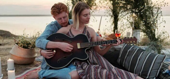 man teaching girlfriend how to play guitar