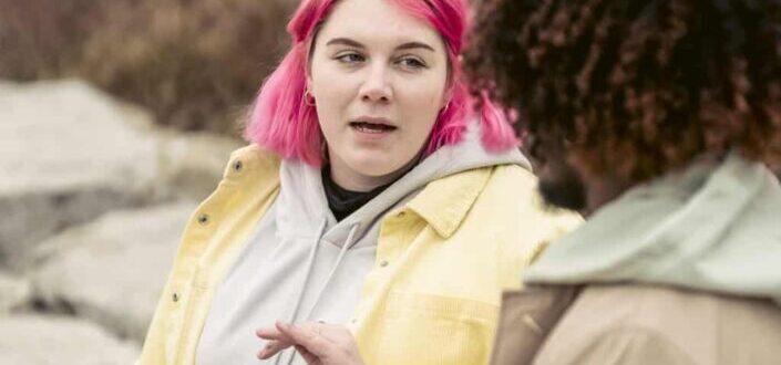 woman in pink hair talking to a man
