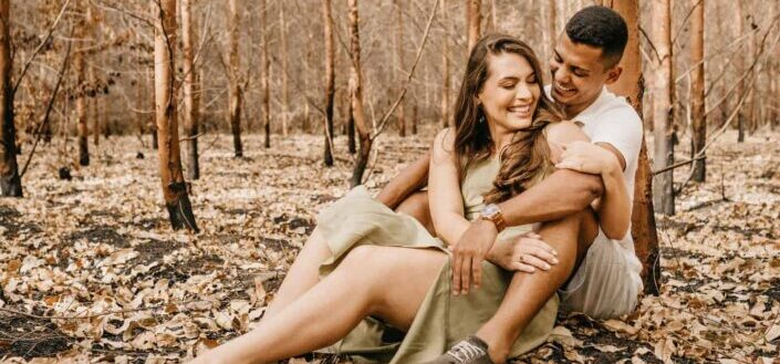 Happy couple hugging sitting on dry leaves