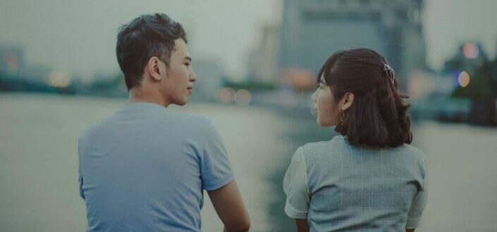 couple talking while facing river