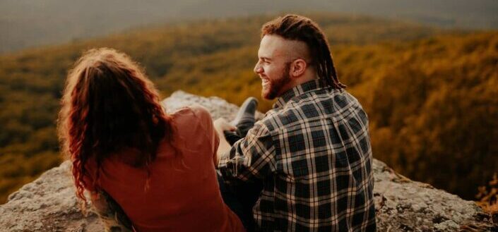 Couple Sitting on a Cliffside During Daytime