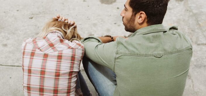 Man and woman sitting on sidewalk