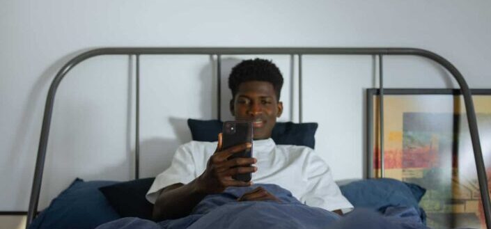 Man Looking at His Phone While Lying Down