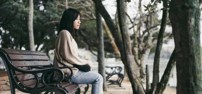 woman sitting on bench near trees