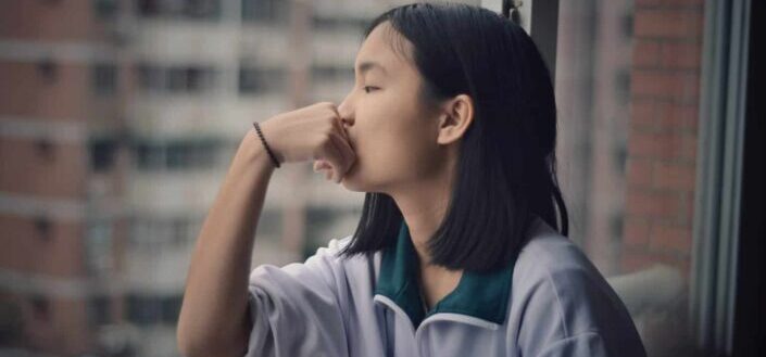Teenage girl standing near window railing