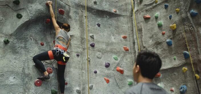 Instructor watching his trainee rock climbing