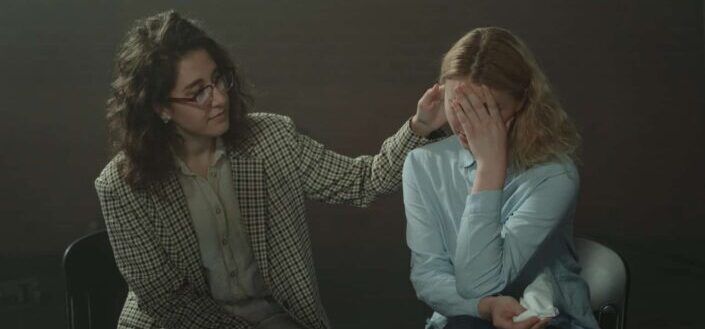 Woman in checkered blazer comforting woman