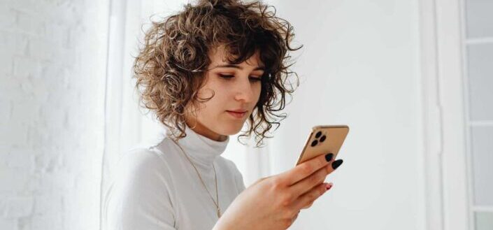Woman in Turtleneck Shirt Using a Cellphone