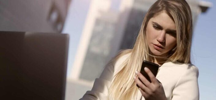Woman in White Blazer Holding Black Smartphone