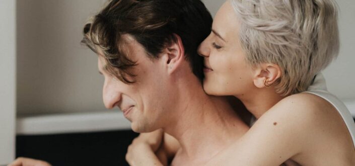 Woman kissing man's nape