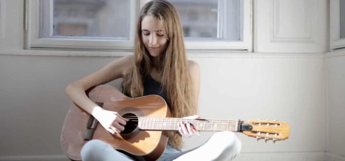 Woman playing brown acoustic guitar