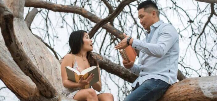 A couple sitting on tree branches while talking
