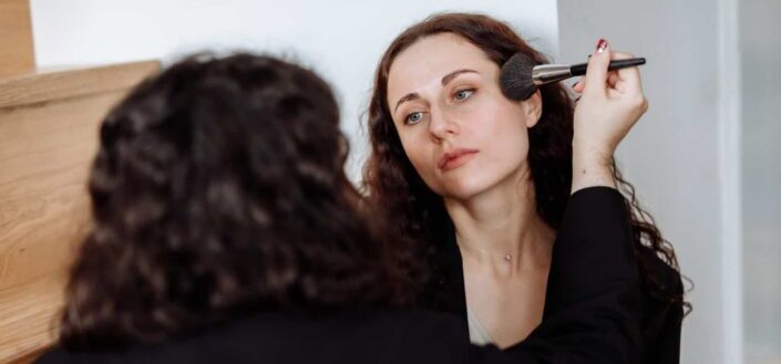A woman holding a brush while applying makeup