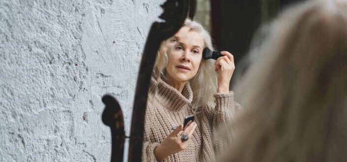 An elderly woman putting on makeup