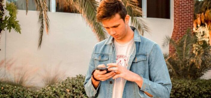 Man in blue denim jacket using phone