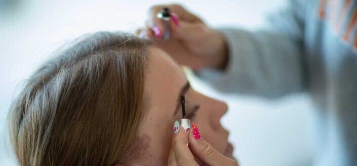 Person applying makeup on a woman's eyebrows