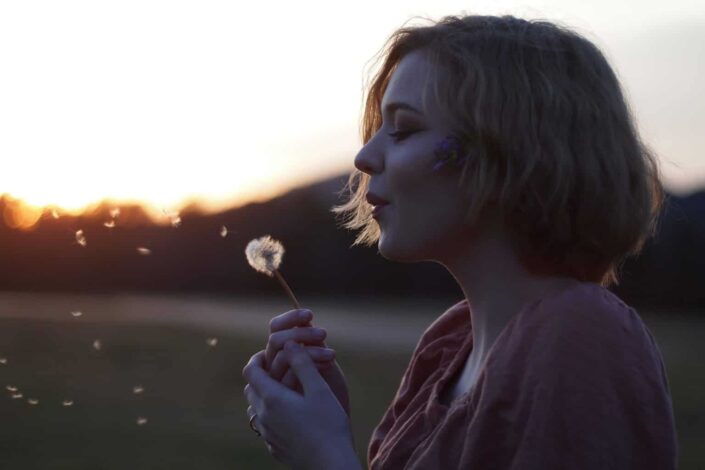 Woman blowing dandelion flowers
