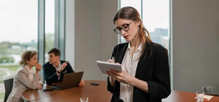 Woman in black blazer writing on notebook