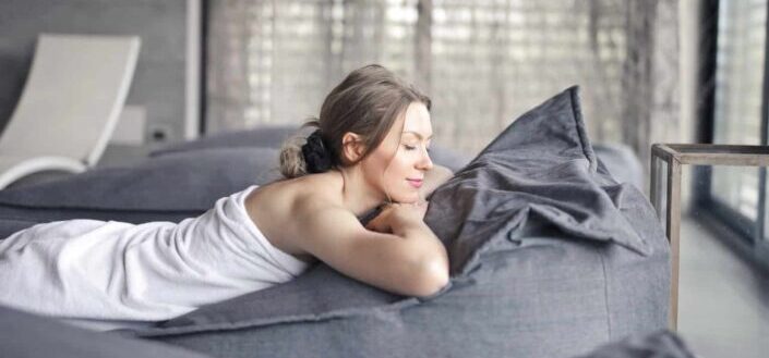 Woman lying on gray bed in spa