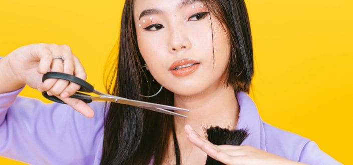Woman using scissors to cut her hair edges