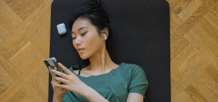 Woman lying on mat using her cellphone