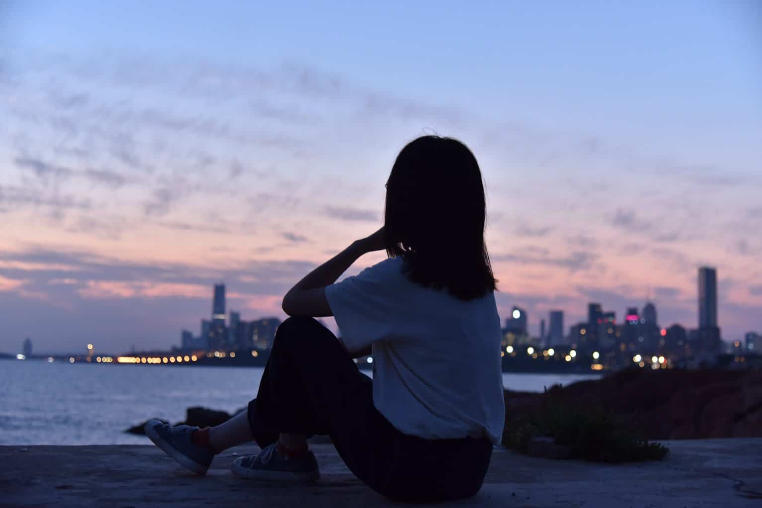 woman sitting in a beach sand during sunset
