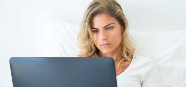 Woman in white shirt using a laptop